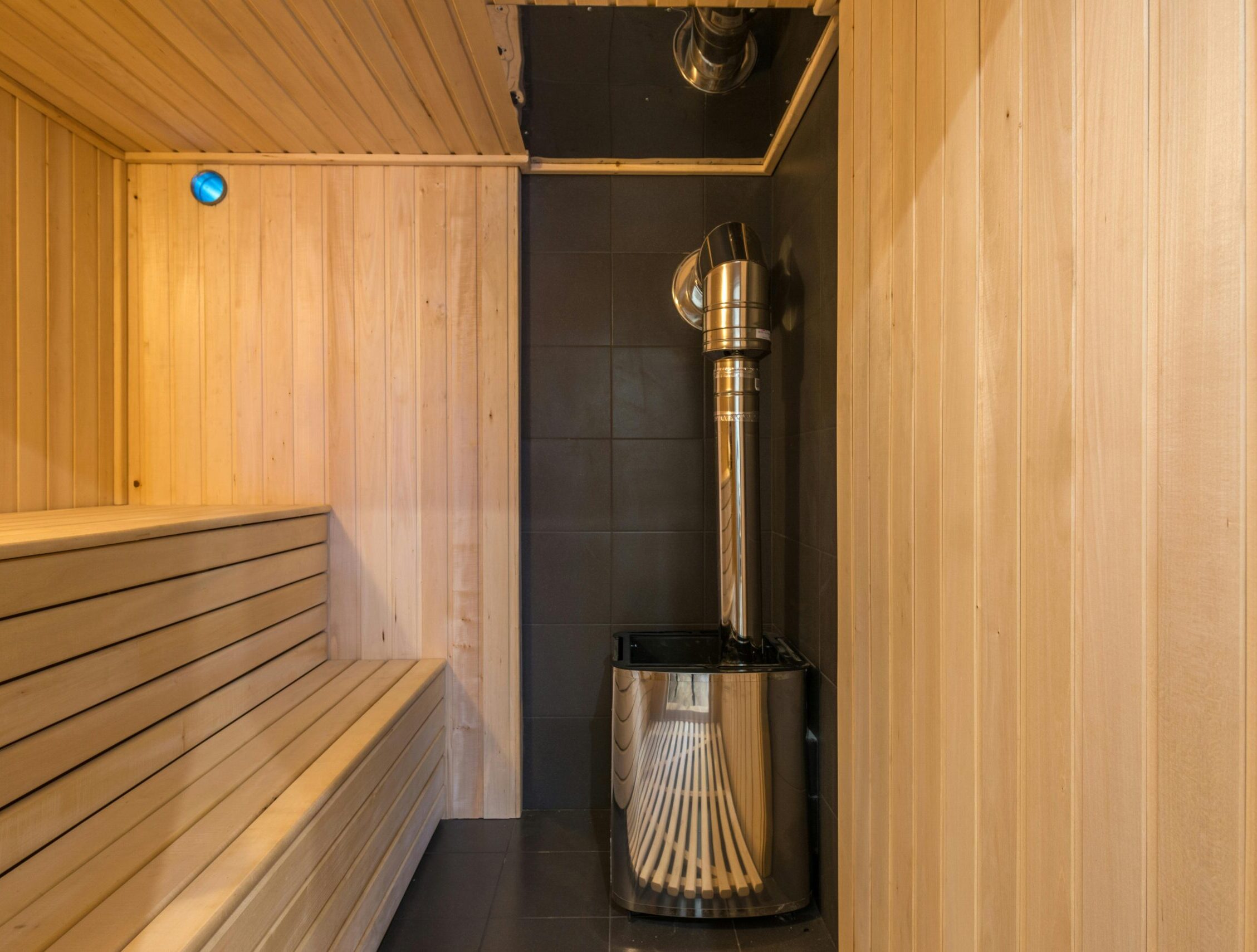 Modern wooden sauna with a sleek metal heater, showcasing luxury home interior design.